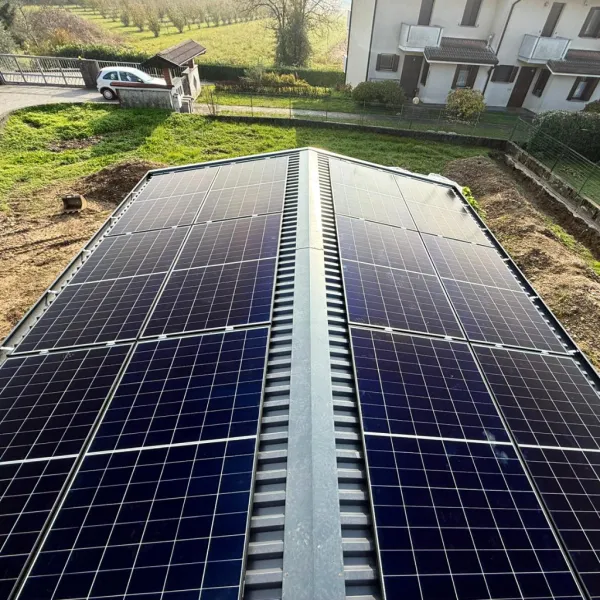 Pannelli fotovoltaici montati su una pensilina per auto in Friuli-Venezia Giulia per la ricarica di veicoli elettrici.